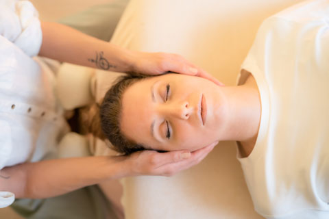 Eine Person, die eine Reiki-Behandlung erhält, eine traditionelle Form der Energieheilung, um Entspannung und geistiges Gleichgewicht zu fördern.